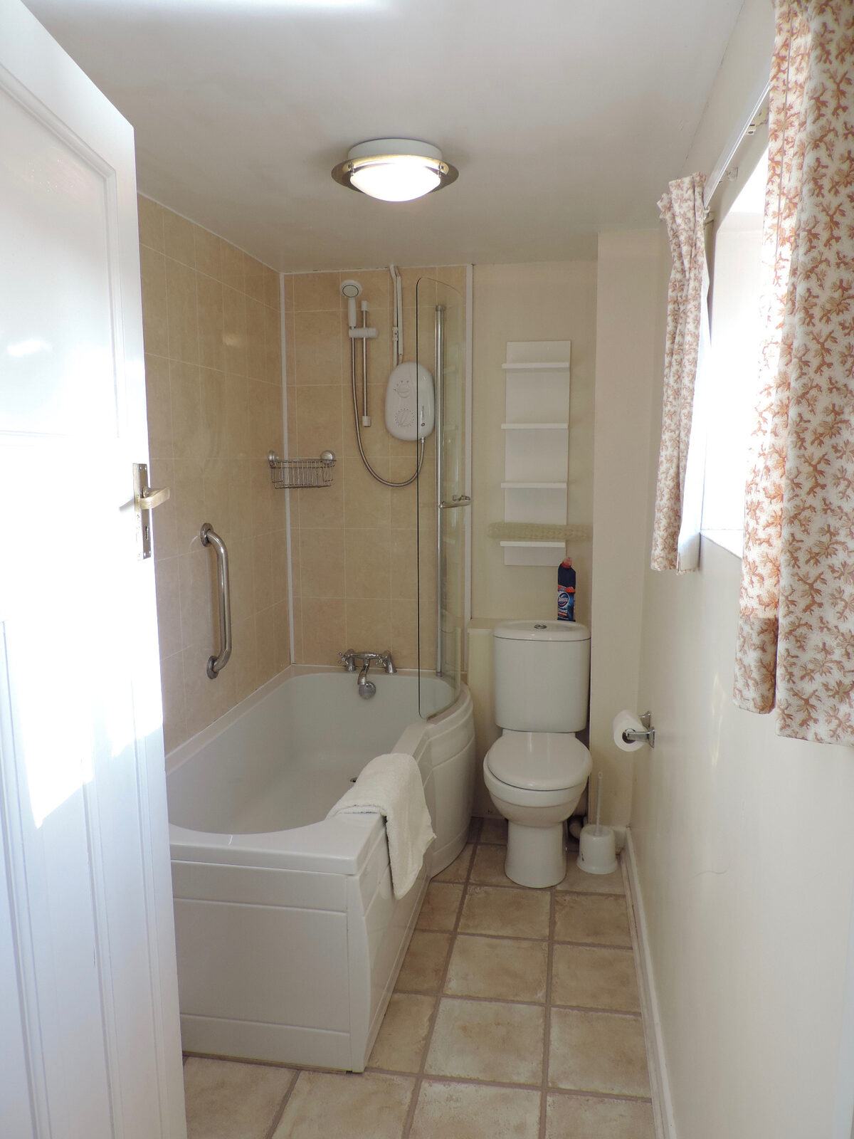 The bathroom with bath and shower in Honeysuckle Cottage